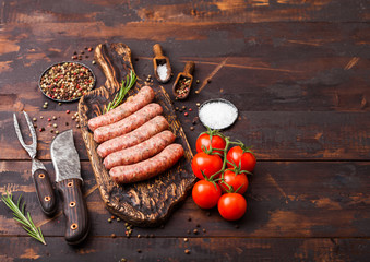 Raw beef and pork sausage on old chopping board with vintage knife and fork on dark wooden...