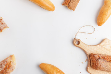 Bread on wooden cutting board isolated on white background, top view