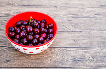 Berries of a sweet cherry on a wooden background in a plastic cup. Ripe red sweet cherry