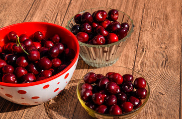 Berries of a sweet cherry on a wooden background in a plastic cup. Ripe red sweet cherry