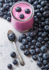 Fresh hommemade creamy blueberry yoghurt with fresh blueberries and silver spoon on stone kitchen table background