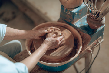 Cropped photo of female hands with clay in workshop
