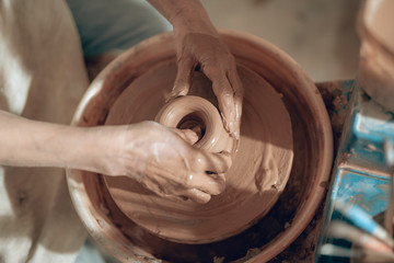 Top view of female hands shaping bowl at workshop