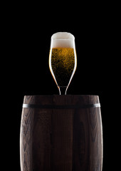 Cold glass of craft beer on old wooden barrel