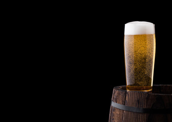 Cold glass of craft beer on old wooden barrel