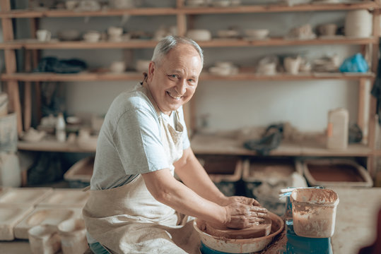 Waist up of elderly craftsman making bowl in potter's studio - Powered by Adobe
