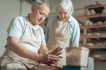 Cropped photo of senior couple in aprons working in potter's studio