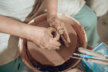 Top view of male hands with clay in potter's studio
