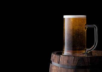 Cold glass of craft beer on old wooden barrel