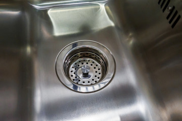 empty and dry metal kitchen sink with grill on drain