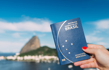 Hand holding Brazilian passport with SugarLoaf Mountain in Rio de Janeiro, Brazil in background