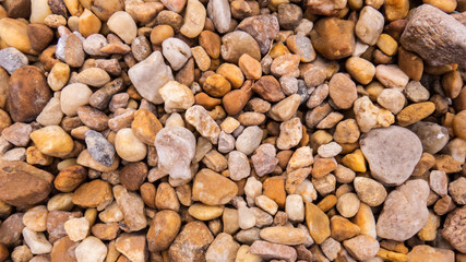 Close-up background of a lot of small stones and pebbles scattered on the ground.