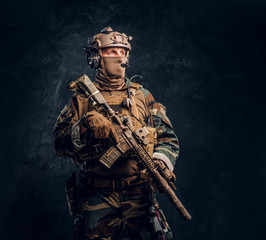 Elite unit, special forces soldier in camouflage uniform posing with assault rifle.