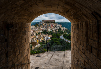 Fototapeta na wymiar Tourist (back view) enjoys cityscape of baroque town Ragusa Ibla in Sicily, Italy