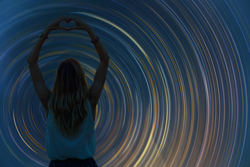 Silhouette of a girl holding heart-shape symbol for love on a starry night sky. My astronomy work.