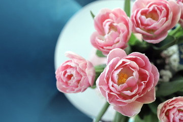 Pink Tulips on a little table with a strong blue background/ backdrop. Colorful interior during Spring.