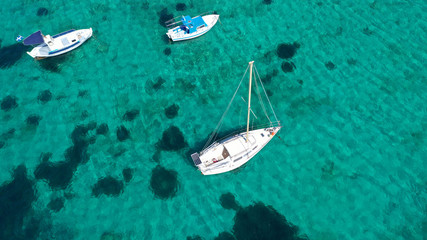 Aerial drone bird's eye view photo of sail boats docked in tropical caribbean paradise bay and turquoise clear sea