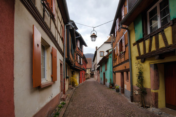 Fototapeta na wymiar A view along the street with old multi-colored half-timbered houses. Alsace. France. Town Kaysersberg. A lantern hangs above the street.