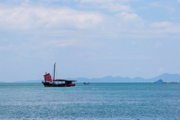 Obraz premium Black sailing ship with red sails sailing on the blue sea.