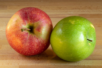 Naklejka na ściany i meble One red apple and one green apple on a wooden board