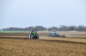 Fototapeta premium Lush and loosen the soil on the field before sowing. The tractor plows a field with a plow