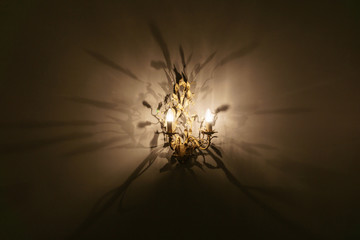 Fototapeta na wymiar antique chandelier with warm light casting numerous shadows on the wall