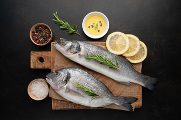 chilled raw fish sea bass and dorado with ingredients on a cutting board against a background of stone