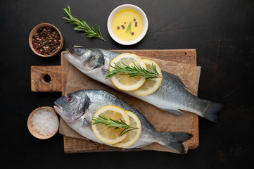 chilled raw fish sea bass and dorado with ingredients on a cutting board against a background of stone
