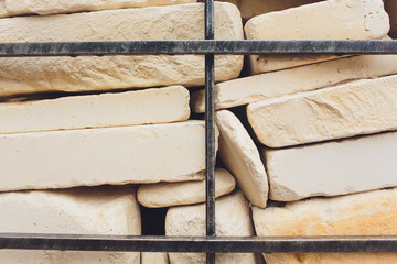 Background fragment of a decorative wall from a granite stone and a metal lattice.