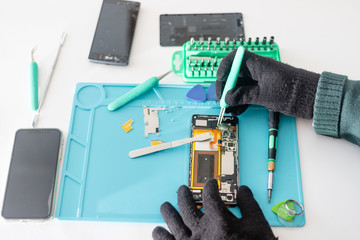 Technician or engineer disassembling components broken smartphone and take off logic board for repair or replace new smartphone logic board on desk