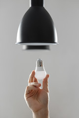Changing the bulb for led bulb in floor lamp in black colour. On light gray background