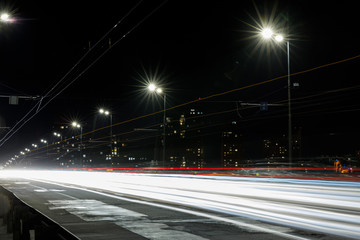 Fototapeta na wymiar long exposure of lights on road at night near buildings