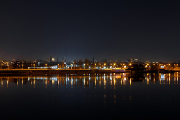 dark cityscape with illuminated buildings and calm river at nigth