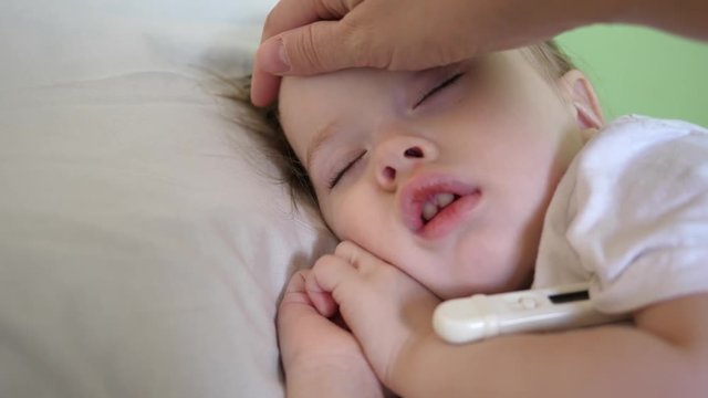 sick kid in bed with a thermometer. the child is sick mom pities the baby. mother next to a sick daughter, the child has fever. Mom cares for the sick child. little girl in the children's hospital