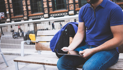 Hipster texting message on tablet computer or technology blank screen mockup. Smile young man using digital on building castle background. Male hands tourist holding gadget on blur cityscape