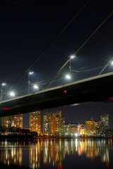 Fototapeta na wymiar bridge, reflection on river and illuminated houses at night