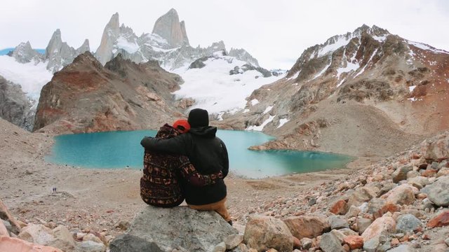 Travelers couple look at the mountain lake. Adventure and travel in the mountains region Patagonia, Fitz roy Mountain. 4k