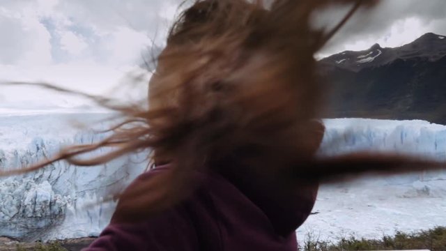 Free young woman carefree and happy with open arms on the background glacier landscape. Perito Moreno Glacier, Patagonia. Slow motion 