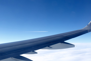 Obraz premium view from the window of the aircraft: part of the wing on the background of another aircraft flying in the distance in the sky