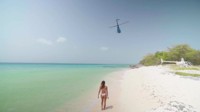 Sexy Woman in Bikini Watches Helicopter Fly Away While on White Sand Beach in Bayahibe, Dominican Republic