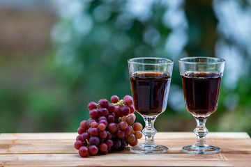 red wine and red grapes on an outdoor wooden table