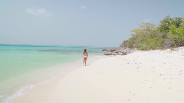 A Fit and Sexy Young Woman in Bikini Walks Along Tropical Shore in Bayahibe, Dominican Republic