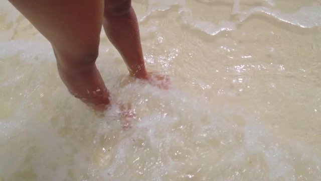 Woman's Legs and Incoming Clear Water Tide in Bayahibe, Dominican Republic