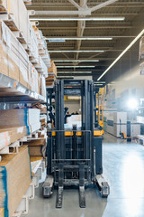 forklift machine in warehouse near racks with wooden construction materials