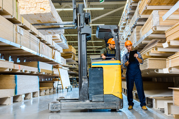 warehouse worker writing in clipboard near indian colleague sitting in forklift machine © LIGHTFIELD STUDIOS