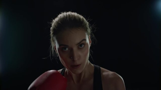 Sport woman doing punches in red boxing gloves at cardio training. Woman boxer