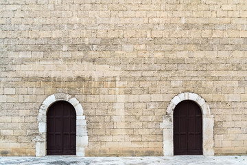 High stone walls with two symmetrical doors, medieval stone background.