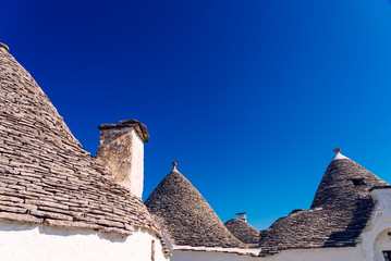 Fototapeta na wymiar Houses of the tourist and famous Italian city of Alberobello, with its typical white walls and trulli conical roofs.