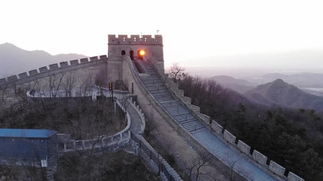 Tower at Great Wall of China at sunset hour, aerial camera move forward. Sun light flick once through doorway at building. Reconstructed fortifications at Badaling site, popular tourist attraction