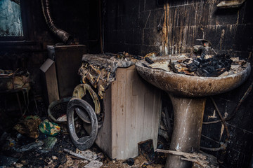 Burnt house interior. Burned burnt bathroom, Fused remains of furniture and washing machine